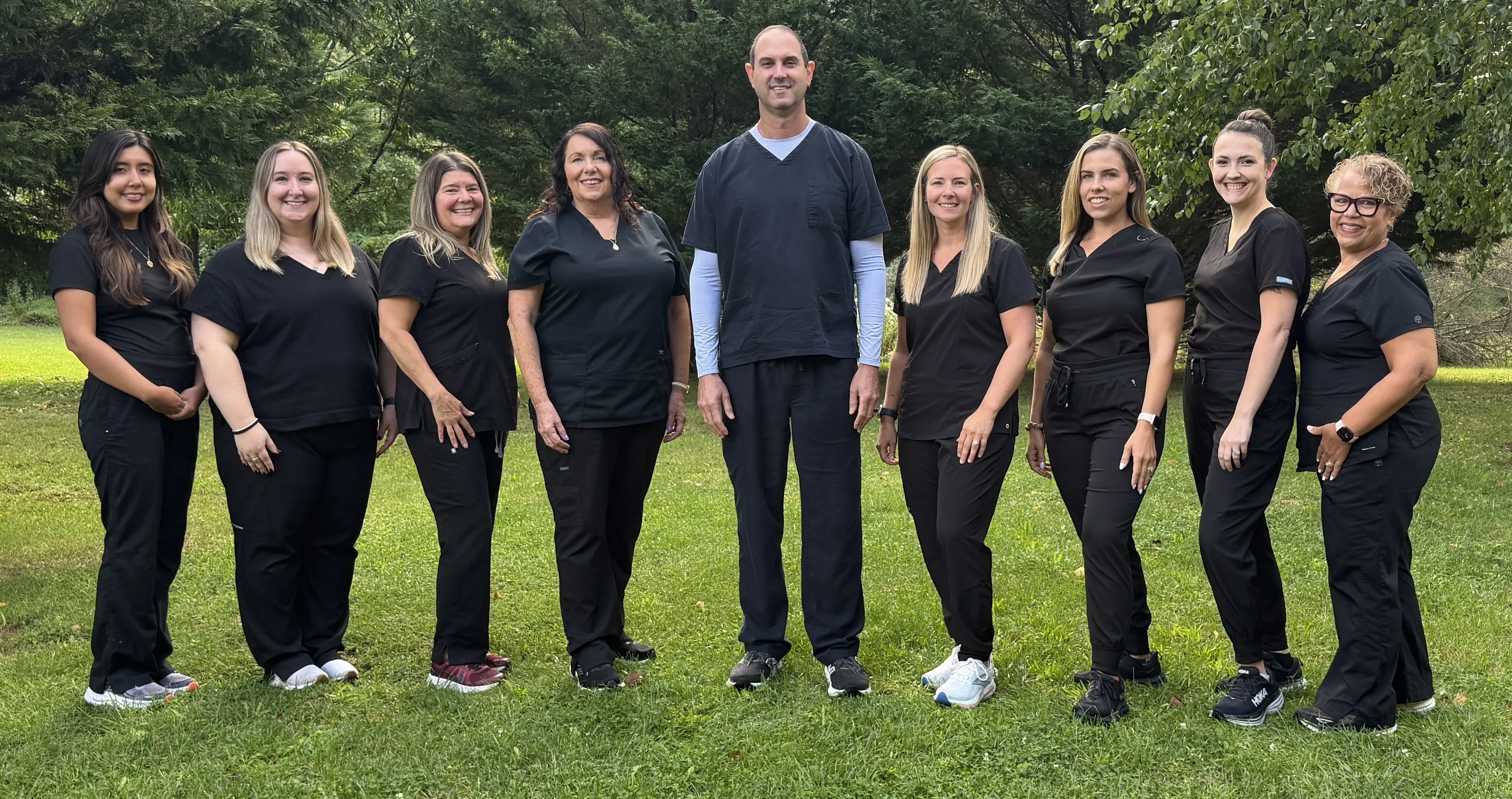 Dr. Adam Klein and the Monroe Dental Group team standing together outdoors